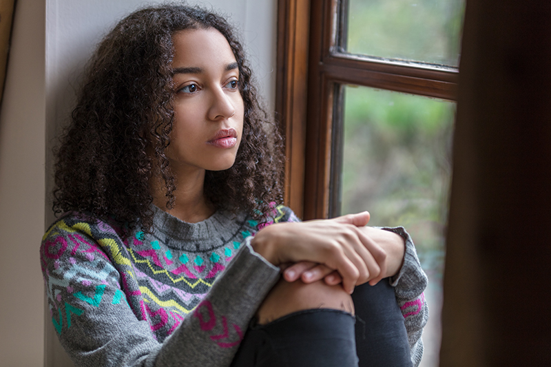 young woman looking out the window in distress